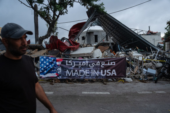 A man walks past a banner on display at the site of an Israeli airstrike in Maaysra, Lebanon.