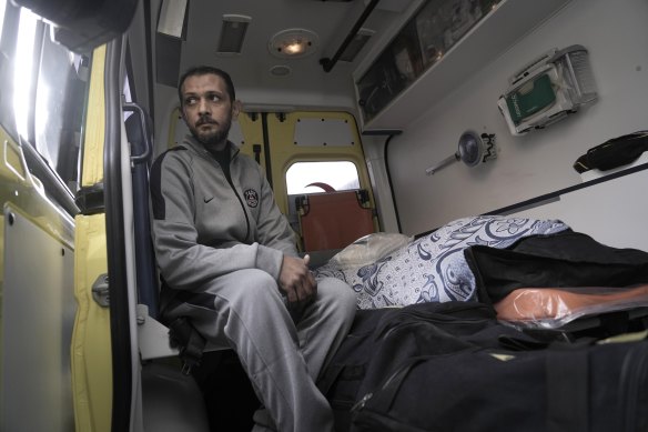 Palestinian Samy Al Bahnasawy sits next to the body of his wife, who died at an Egyptian hospital from injuries sustained during the war. He is pictured crossing back into Gaza.
