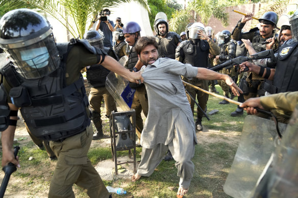 A Khan supporter is detained by police in Lahore in May.