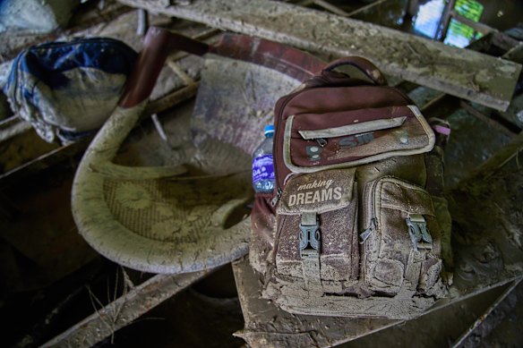 A mud-covered school bag and furniture lies in a classroom damaged in Dhading after the flood.
