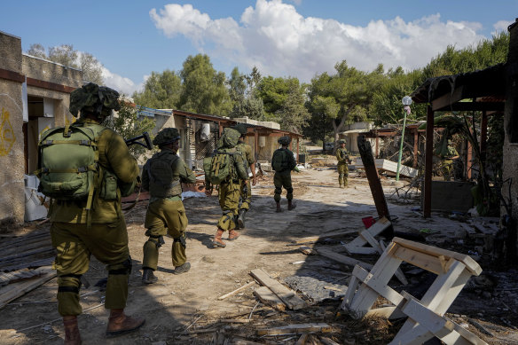 Israeli soldiers patrol next to houses damaged by Hamas militants in Kibbutz Kfar Azza, Israel.
