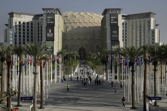 People walk through the venue for the COP28 UN Climate Summit with the Al Wasl Dome in the background at Expo City, Dubai.