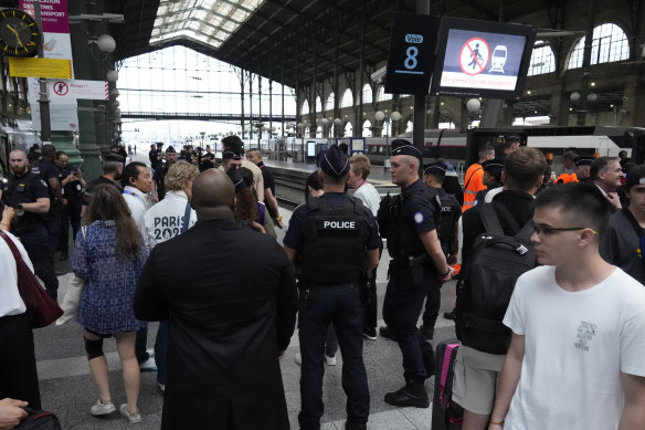 Travellers wait as police officers patrol inside the Gare du Nord train station