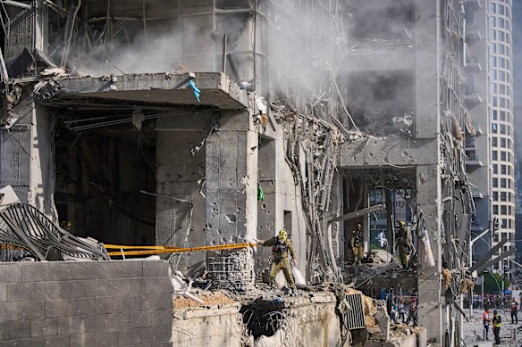 Rescue workers and military personnel inspect the site of a direct hit from an Iranian missile strike in Israel on Thursday.