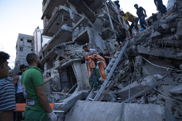 Palestinians rescue a girl from the rubble of a residential building following an Israeli airstrike.