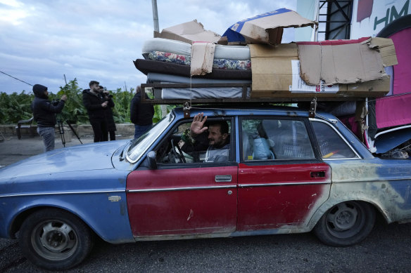 A man who is returning to his village waves as he carries his belongings on his car after the ceasefire.