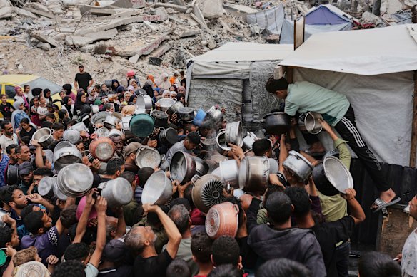 Palestinians struggle to get donated food at a community kitchen in Jabalia.