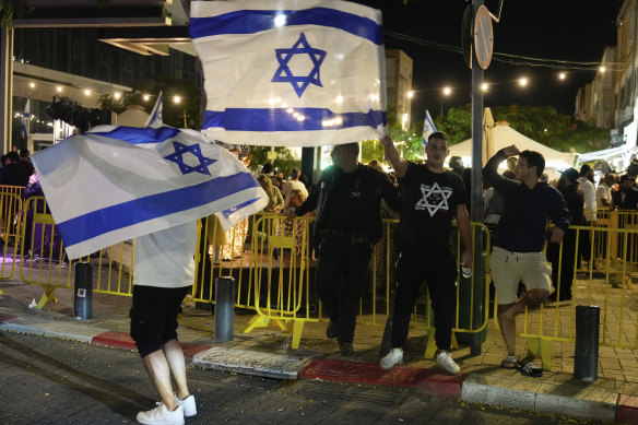 People wave the Israeli flag as they celebrate the news of the death of Hamas leader Yahya Sinwar, in Netanya, Israel.