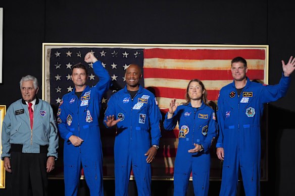 Astronaut Harrison “Jack” Schmitt, from left, Artemis II crew members Reid Wiseman, Victor Glover, Christina Koch and Jeremy Hansen stand on stage as Trump speaks.