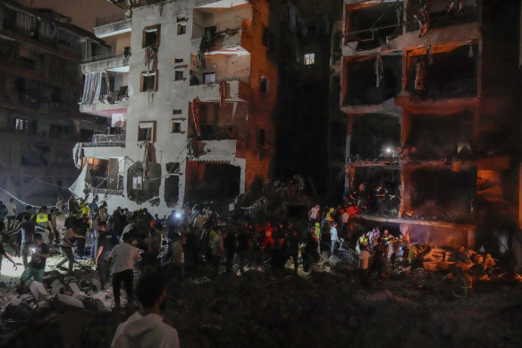 People gather in front of destroyed buildings hit by an Israeli airstrike in central Beirut, Lebanon.