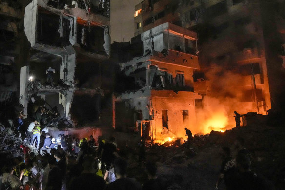 People gather in front of destroyed buildings hit by an Israeli airstrike in central Beirut, Lebanon.