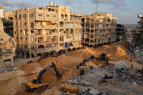 Palestinians watch machinery and some workers from Egypt searching for the bodies of hostages at Hamad City, in Khan Younis, southern Gaza Strip.