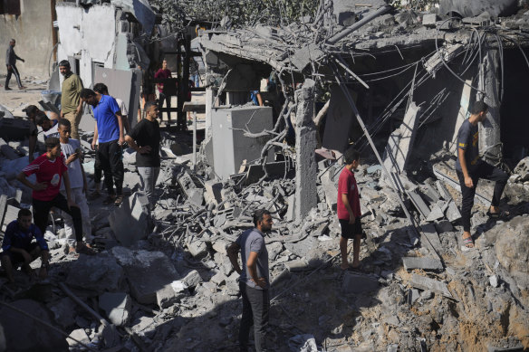 Palestinians look at buildings destroyed in the Israeli bombardment in the morgue in Deir al Balah, Gaza Strip on Tuesday.