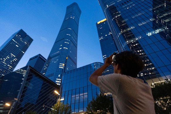 A passerby tries to take photo of the damage to the skyscraper.