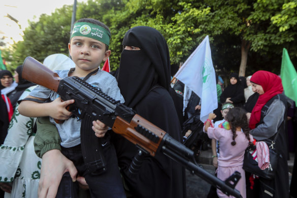 A supporter of the Islamist Hamas movement carries her son, who holds a machine gun toy during a protest in the southern port city of Sidon, Lebanon.