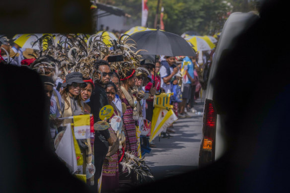 People wait along a road where Pope Francis was expected to pass on his way from the Dili’s Presidente Nicolau Lobato International Airport.