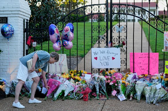 Becky Wangner leaves flowers for a makeshift memorial honoring Dolly Parton outside her home.