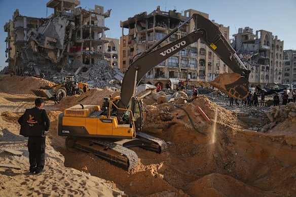 Palestinians watch machinery and workers from Egypt searching for bodies of hostages at Hamad City in southern Gaza.