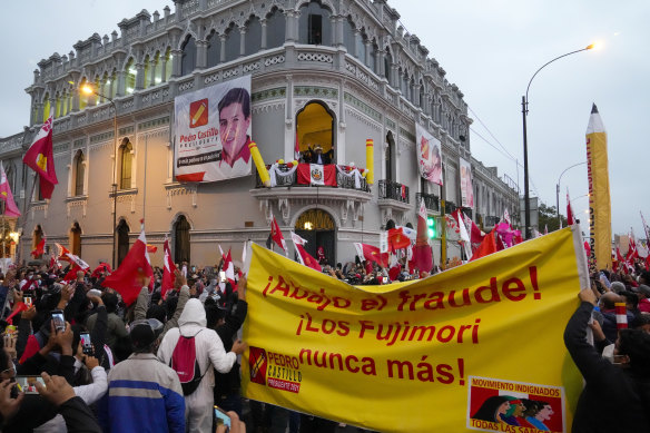 Presidential candidate Pedro Castillo waves to supporters celebrating partial election results. The large banner reads “the Fujimoris never again”.