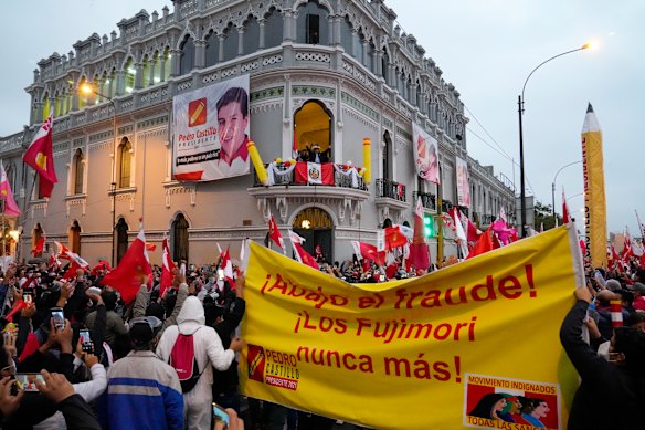 Presidential candidate Pedro Castillo waves to supporters celebrating partial election results. The large banner reads “the Fujimoris never again”.