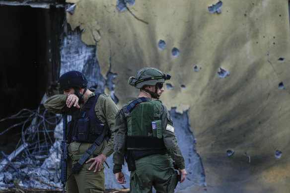 Israeli soldiers walk past houses destroyed by Hamas militants in Kibbutz Be’eri, Israel.