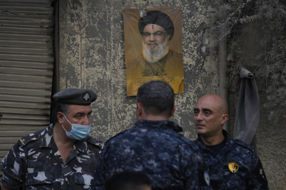Lebanese police stand in front of a portrait shows the late Hezbollah leader, Sayyed Hassan Nasrallah.