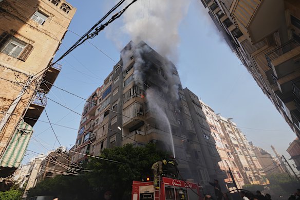 Firefighters spray water on a burning residential building following an Israeli airstrike in central Beirut.
