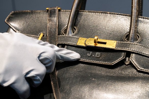 Un empleado de la subasta señala las iniciales de Jane Birkin en el bolso Hermès Birkin original de 1984.