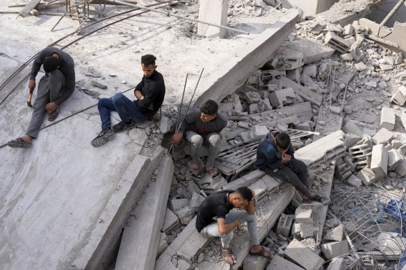 Palestinians sit by the building of the Al-Nadi family destroyed in the Israeli bombardment of the Gaza Strip in Nusseirat refugee camp.