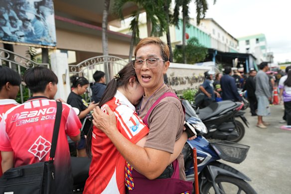 A schoolgirl is comforted outside the school.