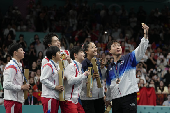 South Korean table tennis players, wearing blue, take a so-called victory selfie on the podium with a team from North Korea.