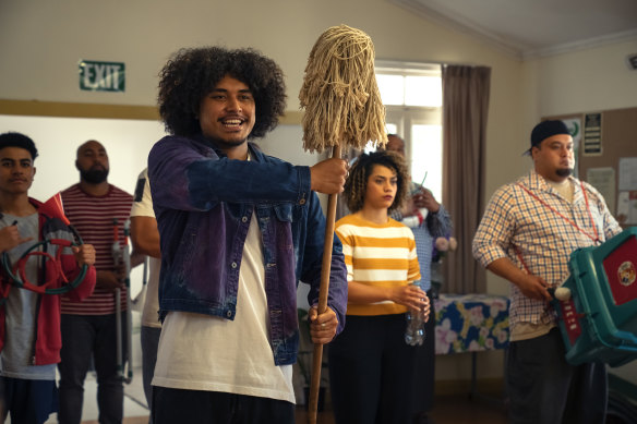 Ringleader Maka (John-Paul Foliaki) holds the mop while the band practice with plastic instruments in Red, White and Brass. 