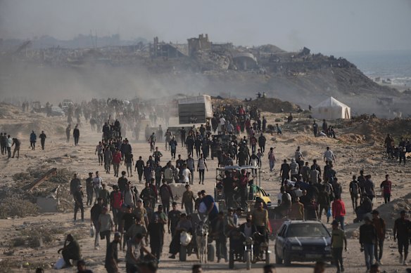Displaced Palestinians walk past the ruins of buildings along the Gaza City shoreline on Monday.