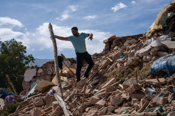 A man removes debris from the rubble of his house in Azgour, Morocco.