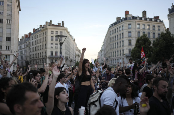 People stand in a square as they react to projected results after the second round of the legislative elections.