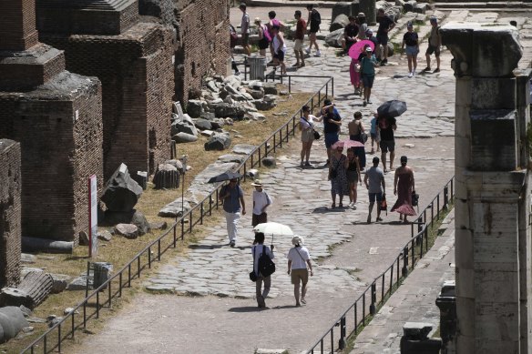 Turistler, Roma'daki Roma Forumu'nda kavurucu bir güneşin altında yürüyorlar.