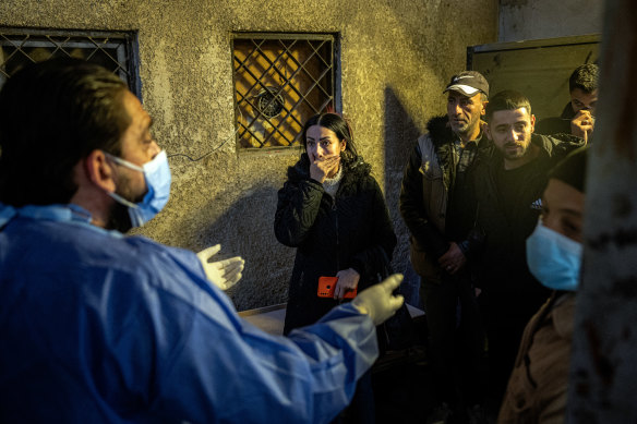 A forensic examiner talks with Syrians desperate for news about missing relatives and loved ones at al-Moujtahid hospital’s morgue.