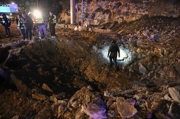 Israeli security forces inspect a damaged road after a missile launched from Iran struck Jerusalem.