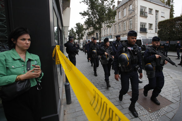 Riot police officers patrol the area after a man armed with a knife killed a teacher and wounded two others at a high school in northern France,