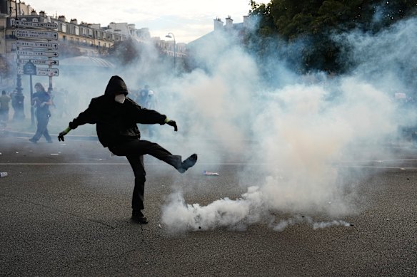 Un manifestante ha preso a calci un lacrimogeno durante le proteste di martedì a Parigi.