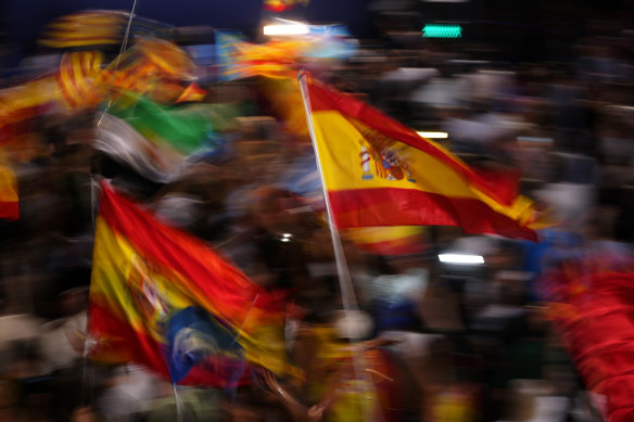 Supporters of Spain’s mainstream conservative People’s Party wave flags.