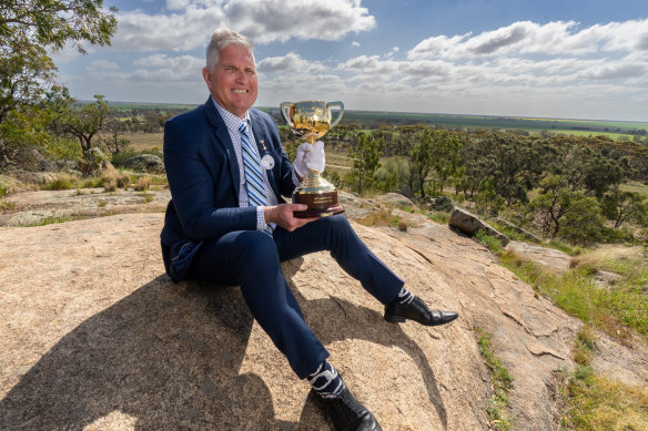 Melbourne Cup tour ambassador Merv Keane holds the famous trophy at the top of Mount Wycheproof.