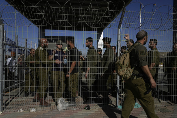 Israeli soldiers gather at the gate to the Sde Teiman military base, where inside, soldiers are being questioned for detainee abuse.