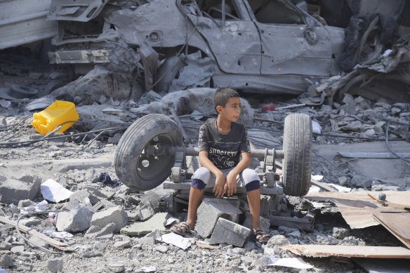 A Palestinian boy sits on the rubble of his building destroyed by an Israeli airstrike in Gaza.
