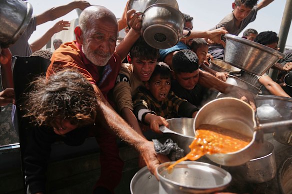Palestinians struggle to get donated food at a community kitchen in Khan Younis on Sunday, May 11.