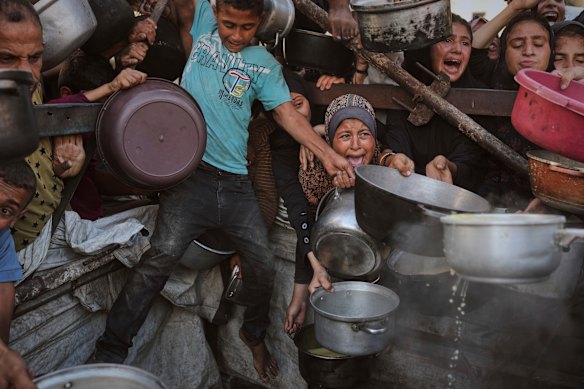 Palestinians struggle to get donated food at a community kitchen in Gaza.