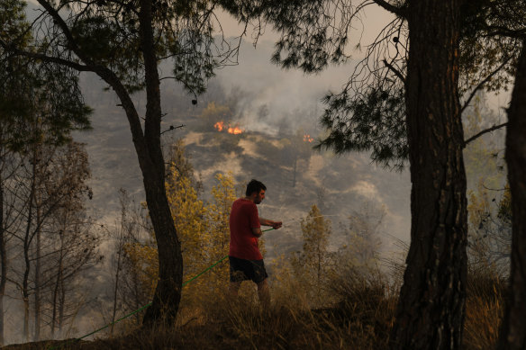 A man tries to extinguish a fire with a hose near Loutraki 80 kilometres west of Athens.