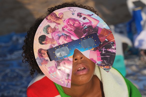 A beachgoer wearing special eclipse glasses looks up from Puerto de Sagunto beach near Valencia, Spain.