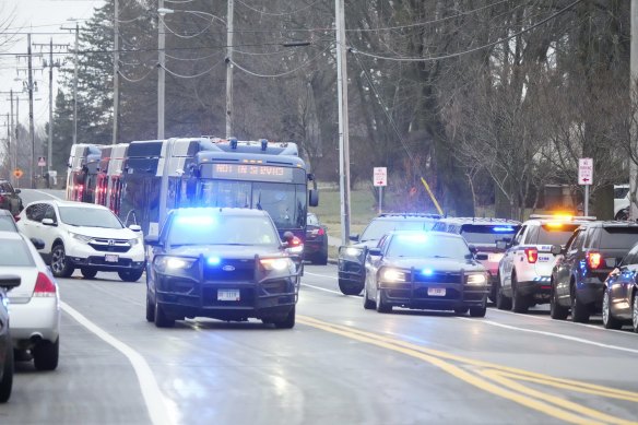 A bus carrying students passes emergency vehicles parked outside the Abundant Life Christian School after the shooting.