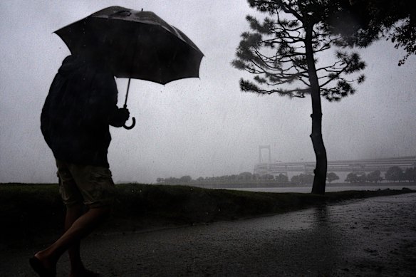 A pedestrian walks through Odaiba Beach as Typhoon Dujuan approaches.